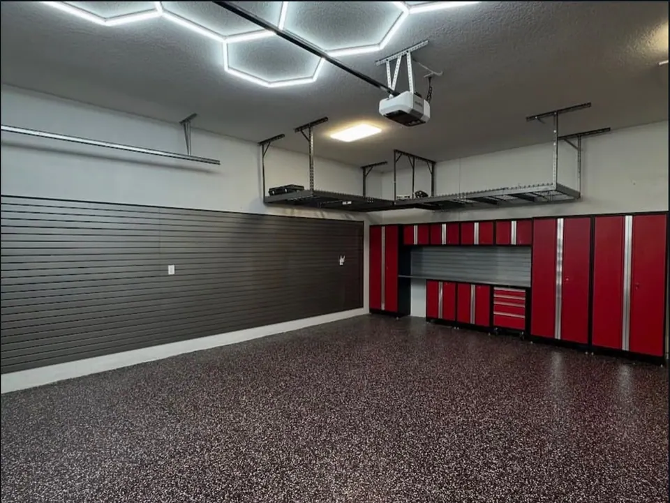 Garage with hex lighting, overhead storage racks, cabinets, and finished floor