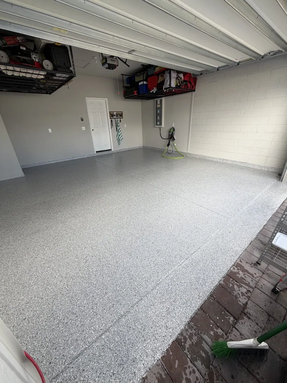 Gray flake garage floor coating with ceiling-mounted storage racks